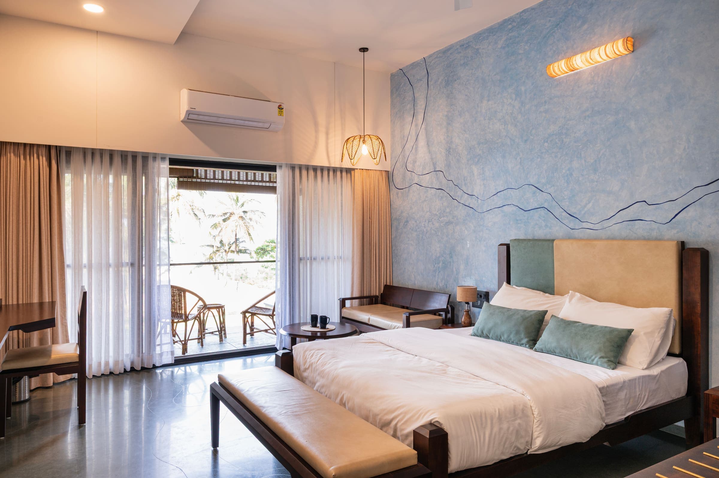 Swarna, in river blue, with its queen bed framed by the balcony doors