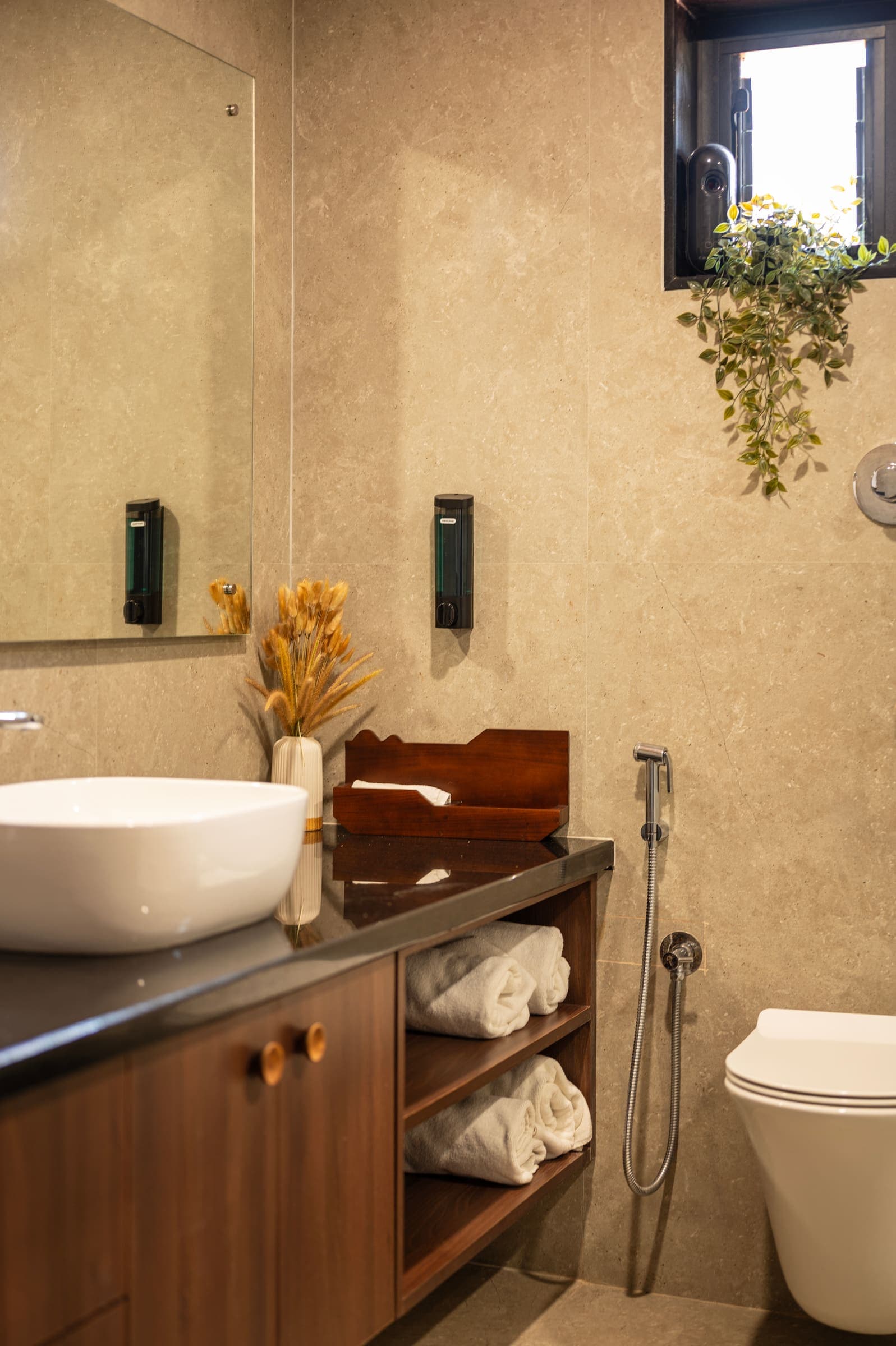 The Varahi bathroom vanity by the window, with folded towels and a potted plant